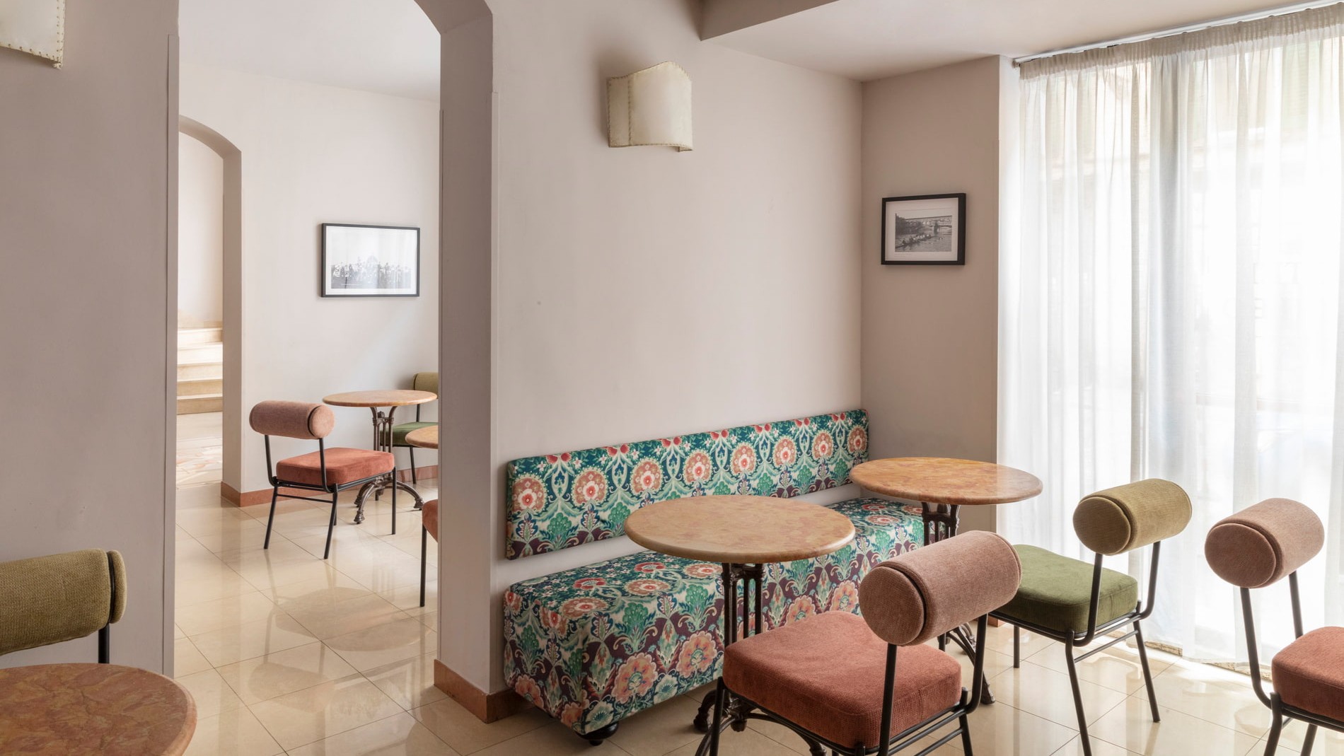 Elegant breakfast room at the hotel in Florence, with a floral patterned bench, round tables, and orange and green fabric chairs - The Galileo Hotel, BZAR hotels in Florence